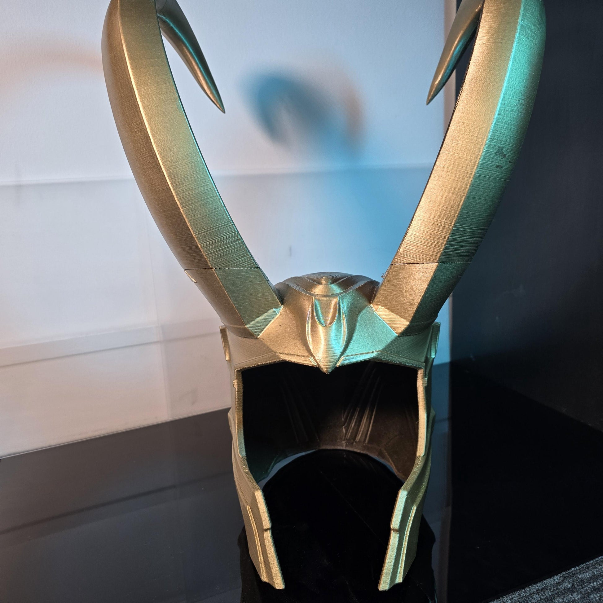 A Loki helmet with detachable horns and a metallic finish, displayed against a neutral background.